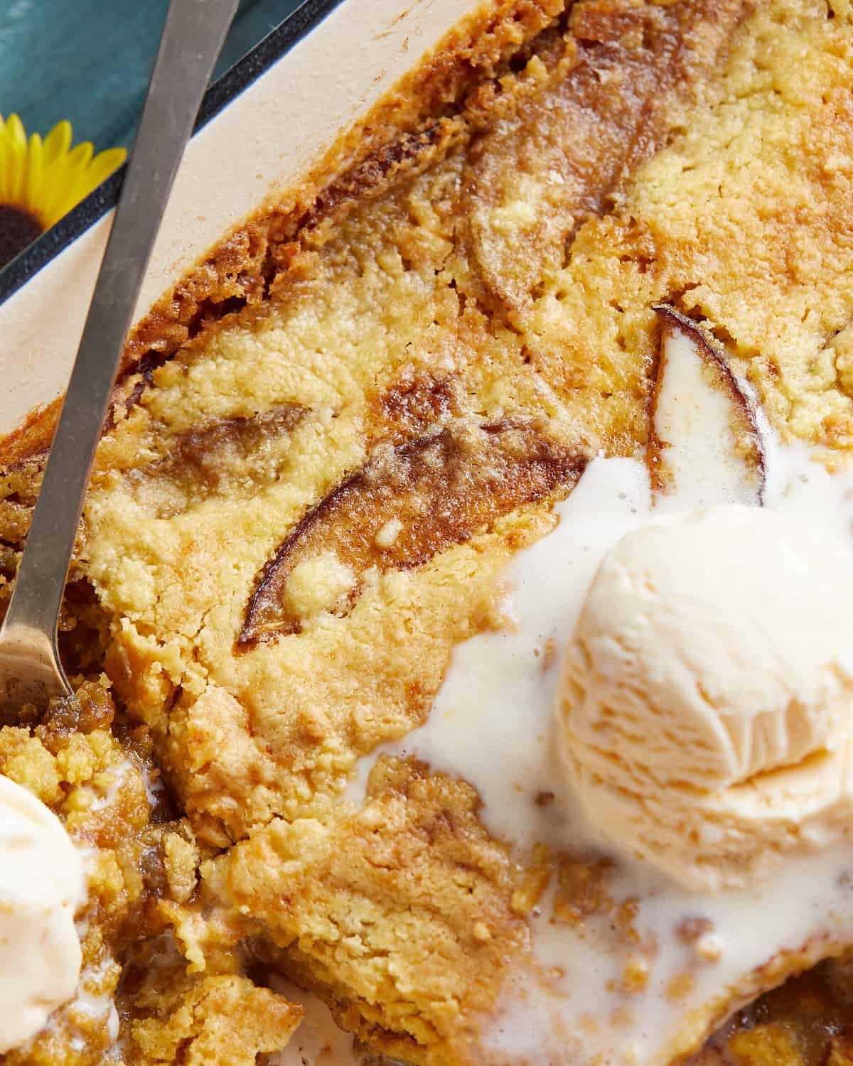Up close image of peach dump cake with ice cream topping.