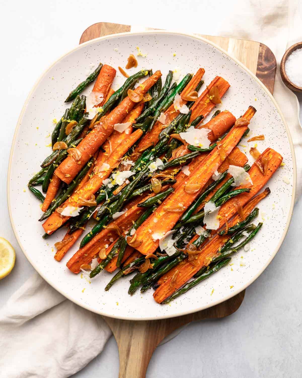 Roasted green beans and carrots on a white plate.