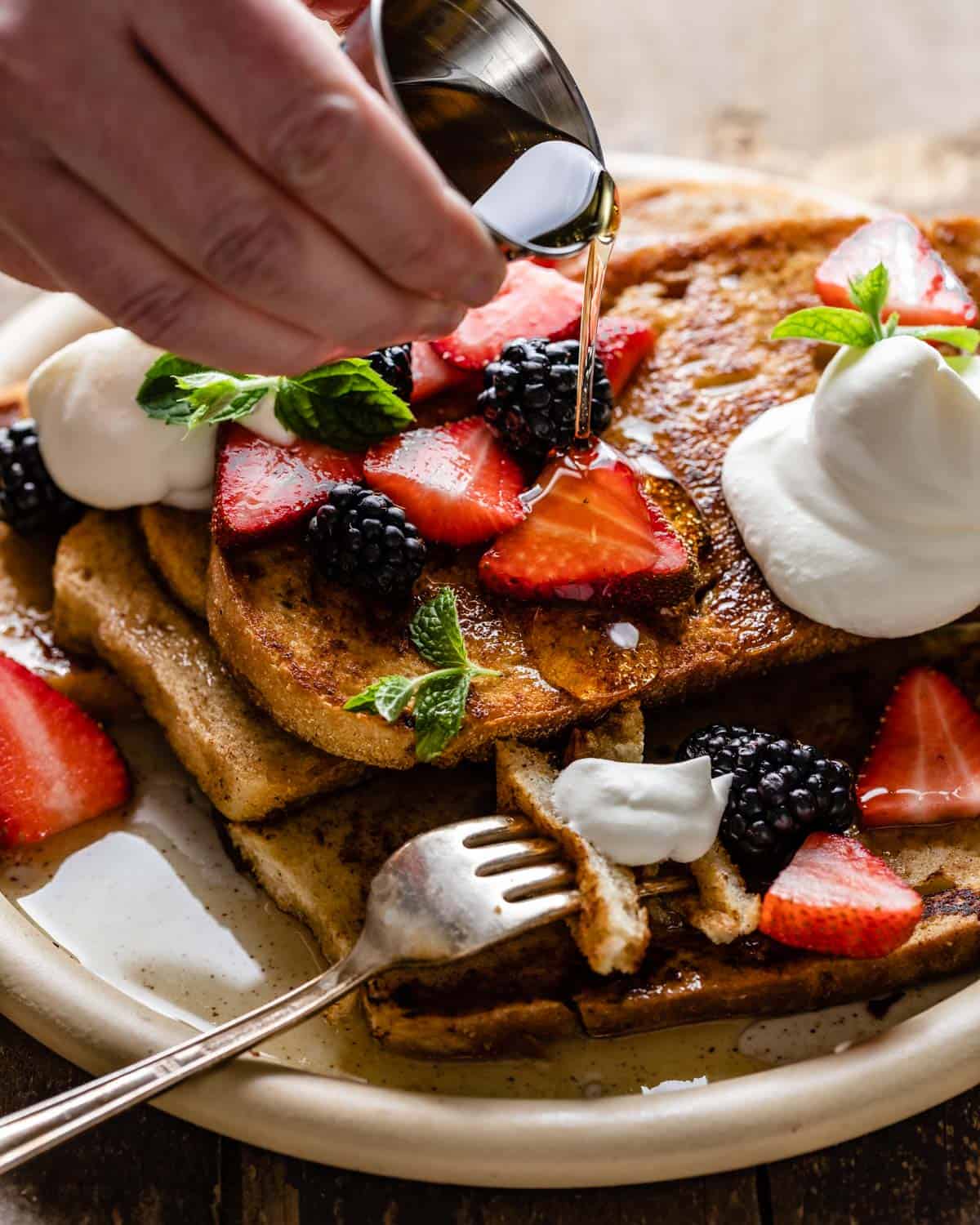 Sourdough french toast stacked with cream and berries.