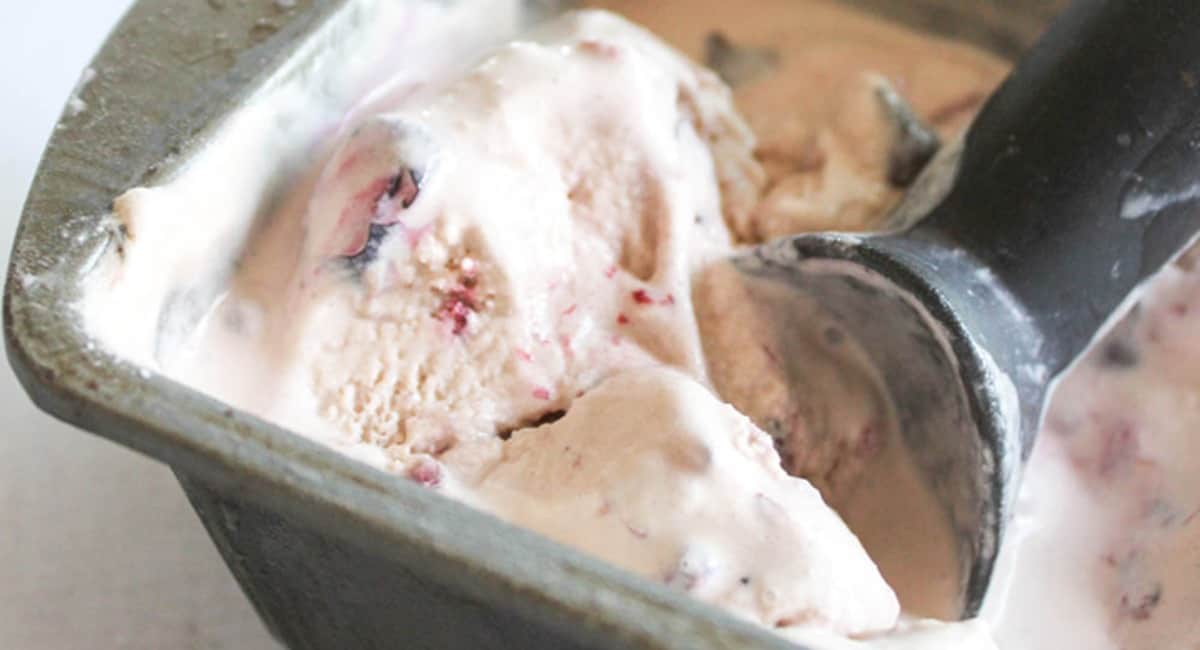 Mixed berry ice cream with chocolate chips being scooped with an ice cream scooper.