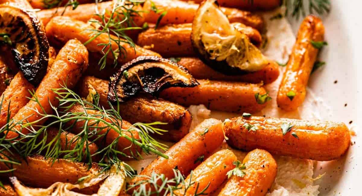 Baby carrots right out of the air fryer on a white plate.