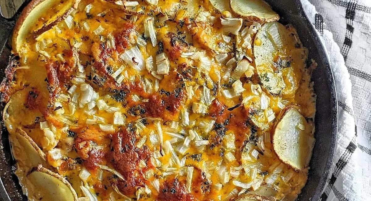 Cheesy potato bake in a black pan.