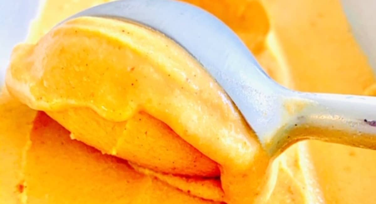 Pumpkin ice cream being scooped by an ice cream scooper.