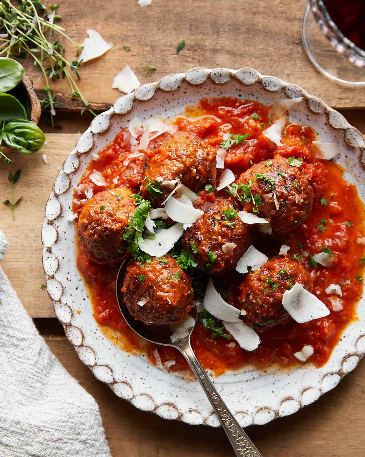 Air fryer frozen meatballs tossed in tomato sauce on a white plate. 