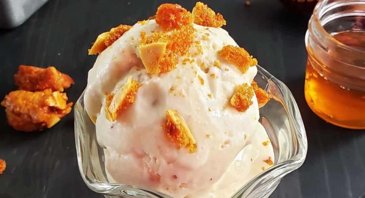 Honey and almond ice cream topped with toasted almonds in a glass bowl.