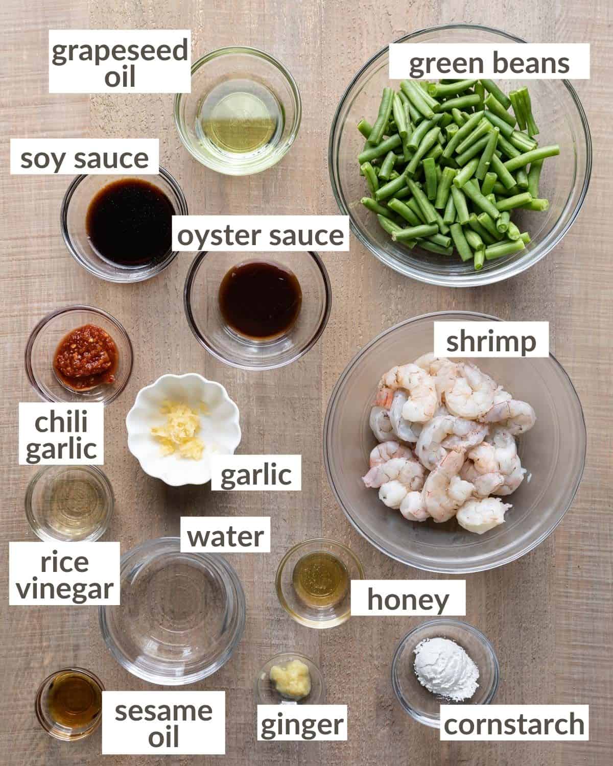 Overhead shot of all ingredients in glass bowls needed to make hunan shrimp. 
