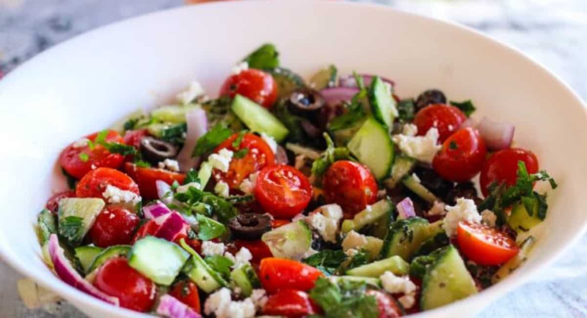 Mediterranean cucumber and tomato salad in a white bowl.