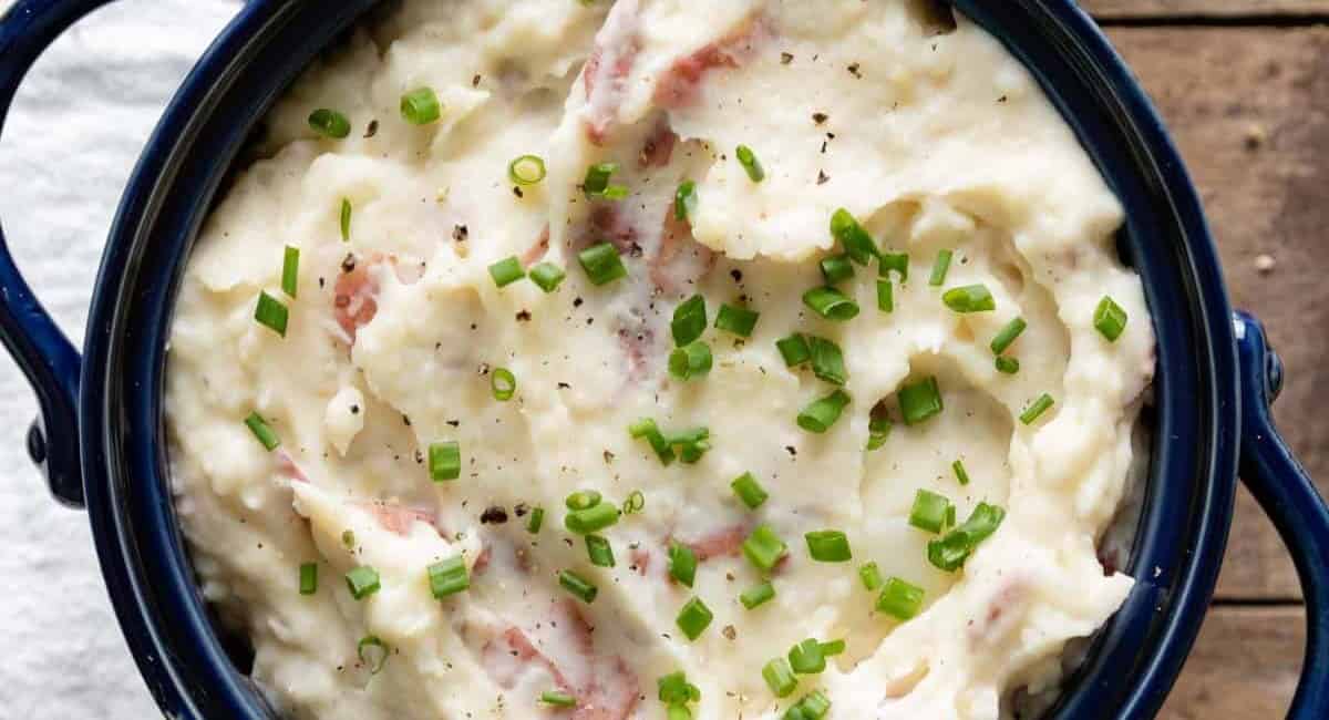 Mashed potatoes topped with scallions and served in a blue bowl.