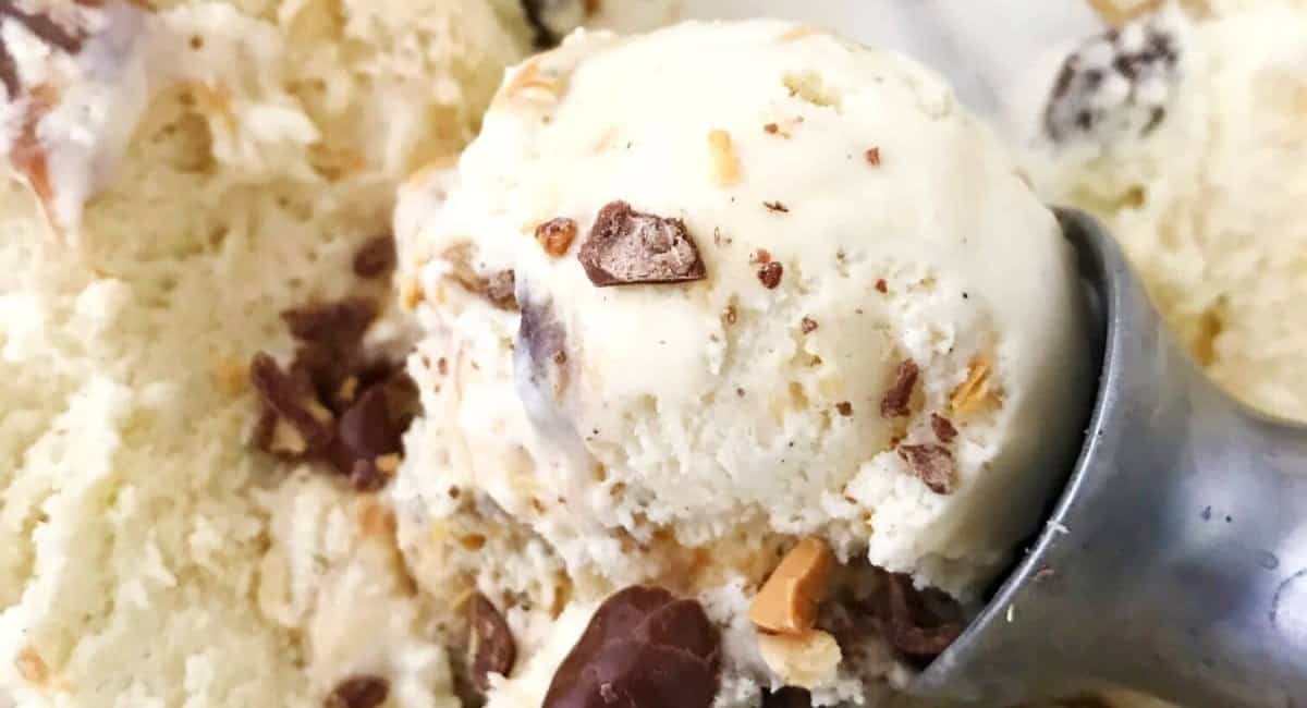 Salted caramel ice cream topped with chocolate covered peanuts in an ice cream scoop.