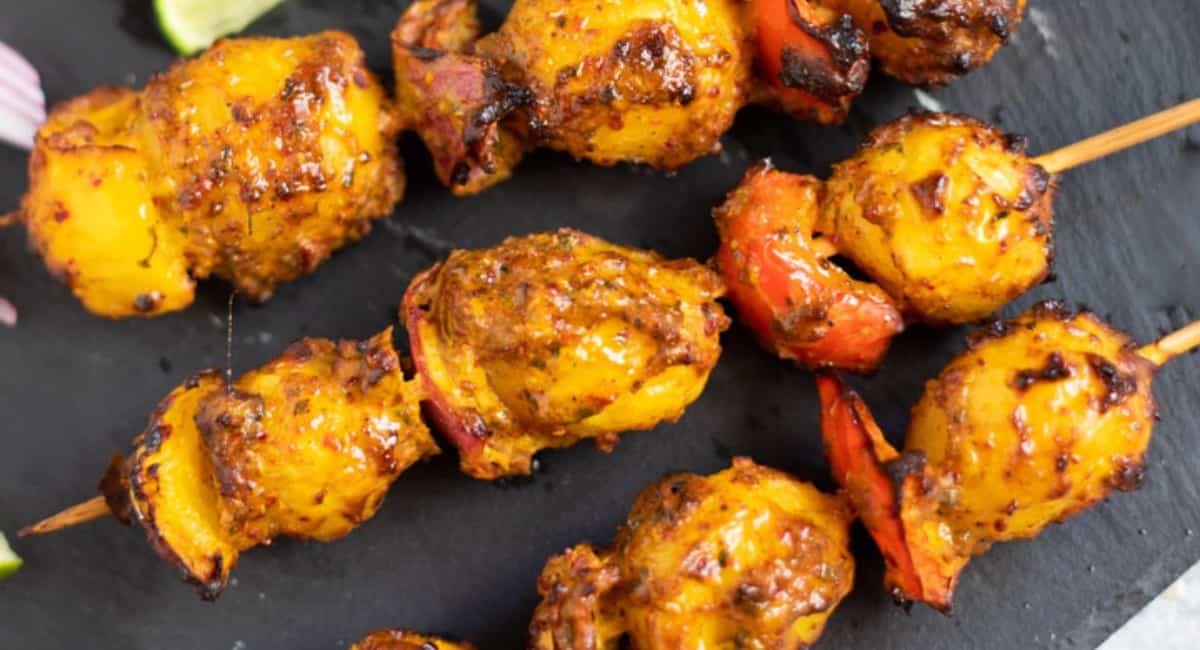 Tandoori aloo tikka skewers on a black mat fresh out of the instant pot air fryer.