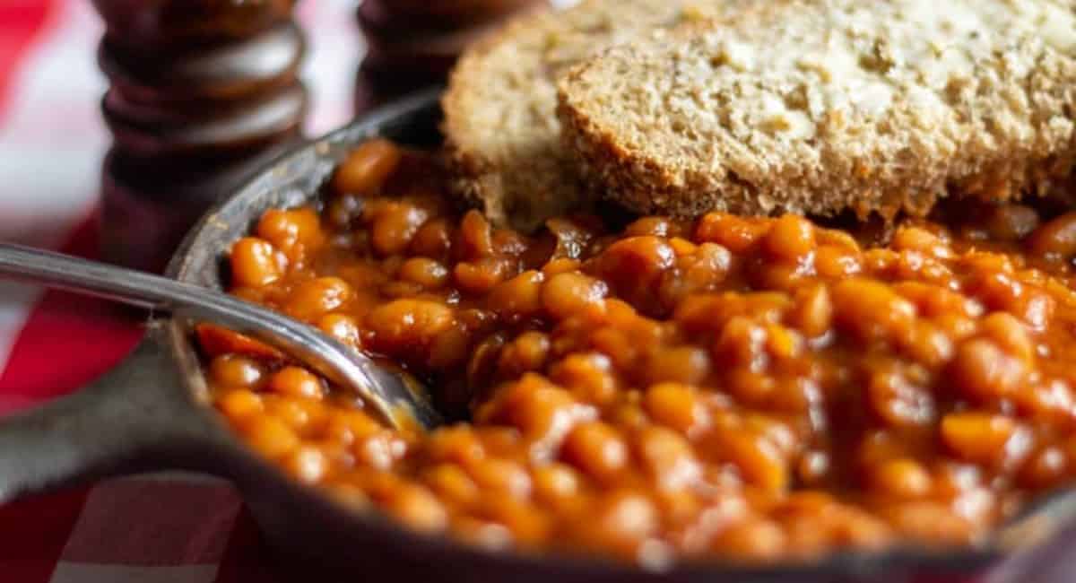 Baked beans in a black pan and topped with bread.