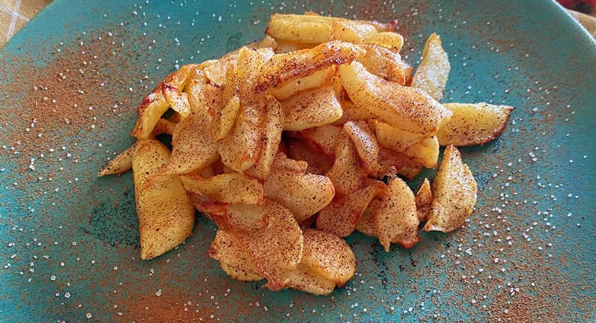 Fried apples served on a blue plate and dusted with cinnamon sugar.