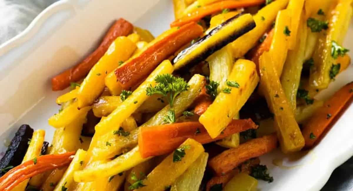 Honey roasted yellow and orange rainbow carrots in a white serving bowl.