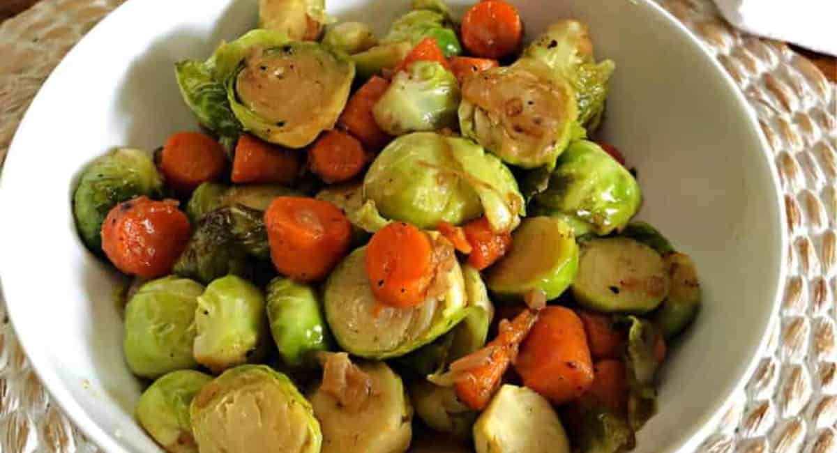 Brussel sprouts and carrots in a white bowl.