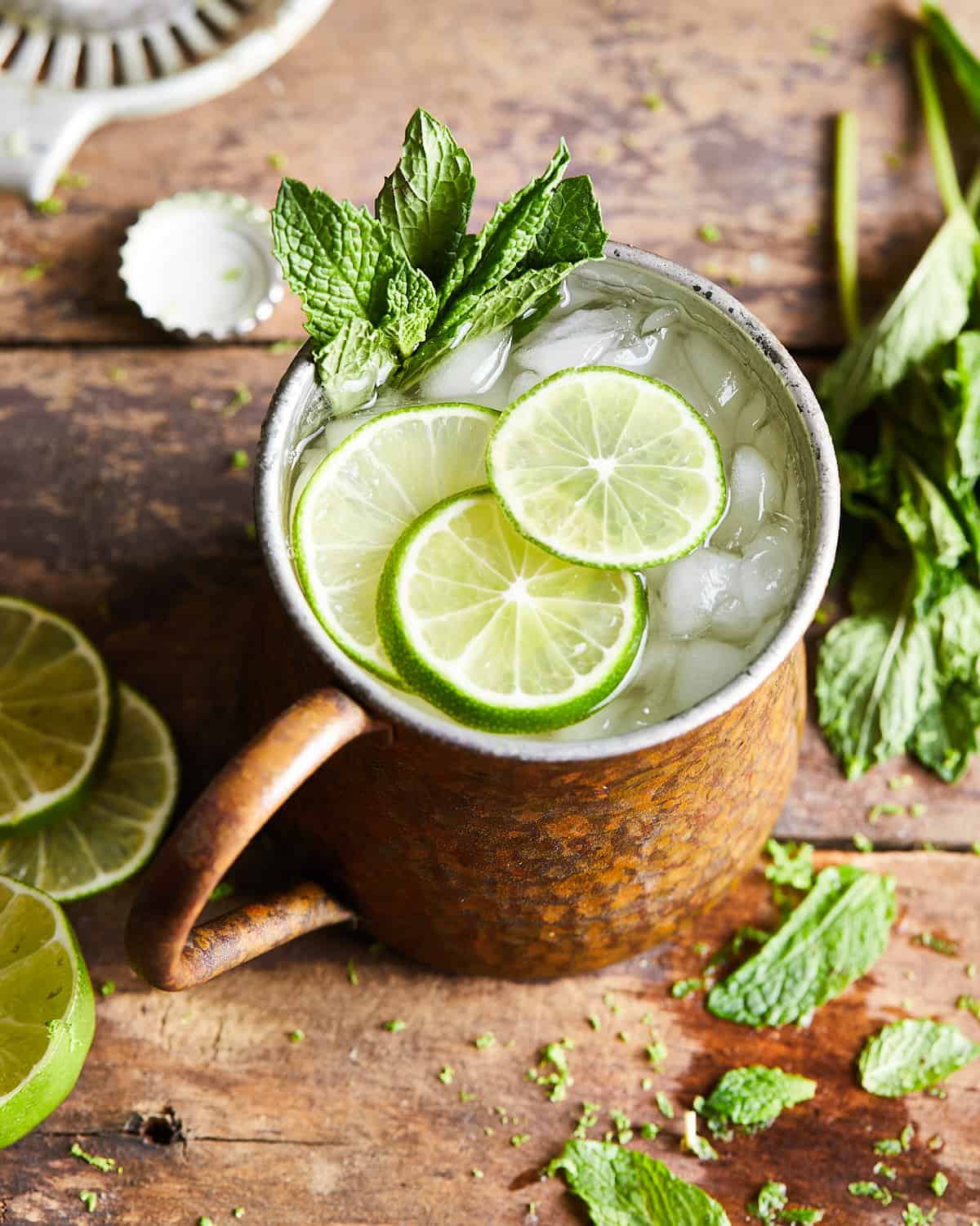 ¾ shot of rum moscow mule in a copper mug with limes and mint leaves on top.