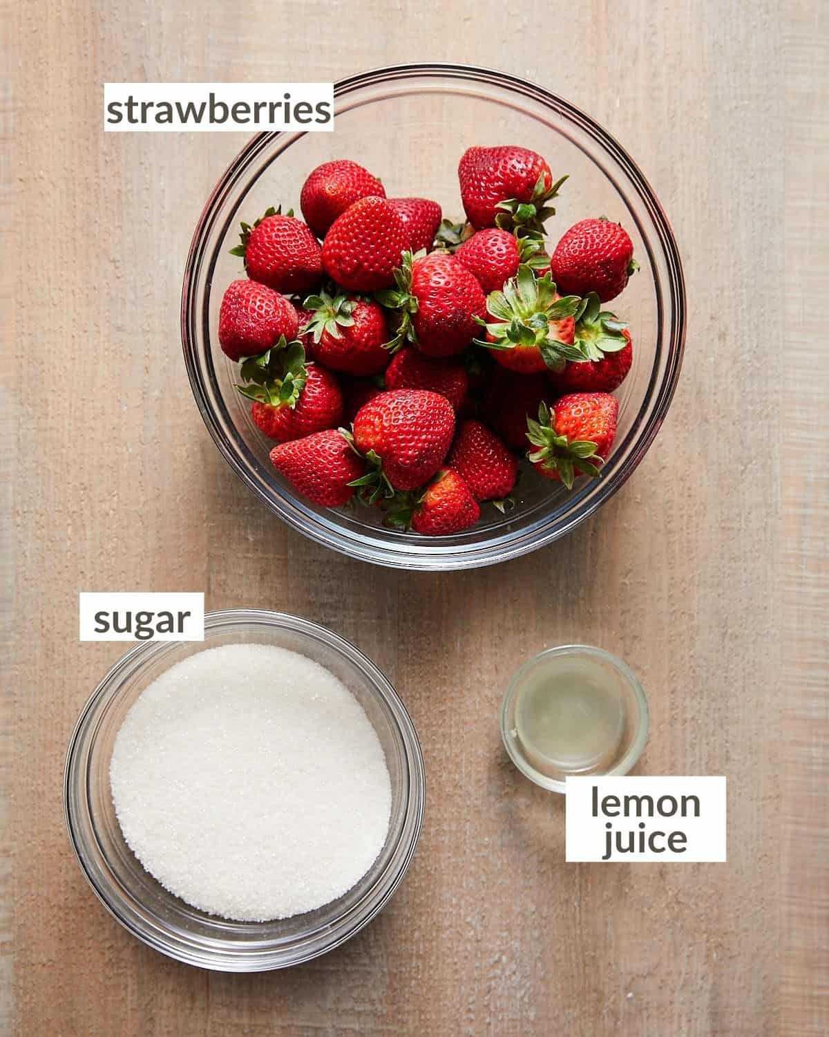 Shows the ingredients needed for strawberry jam recipe in glass bowls. 