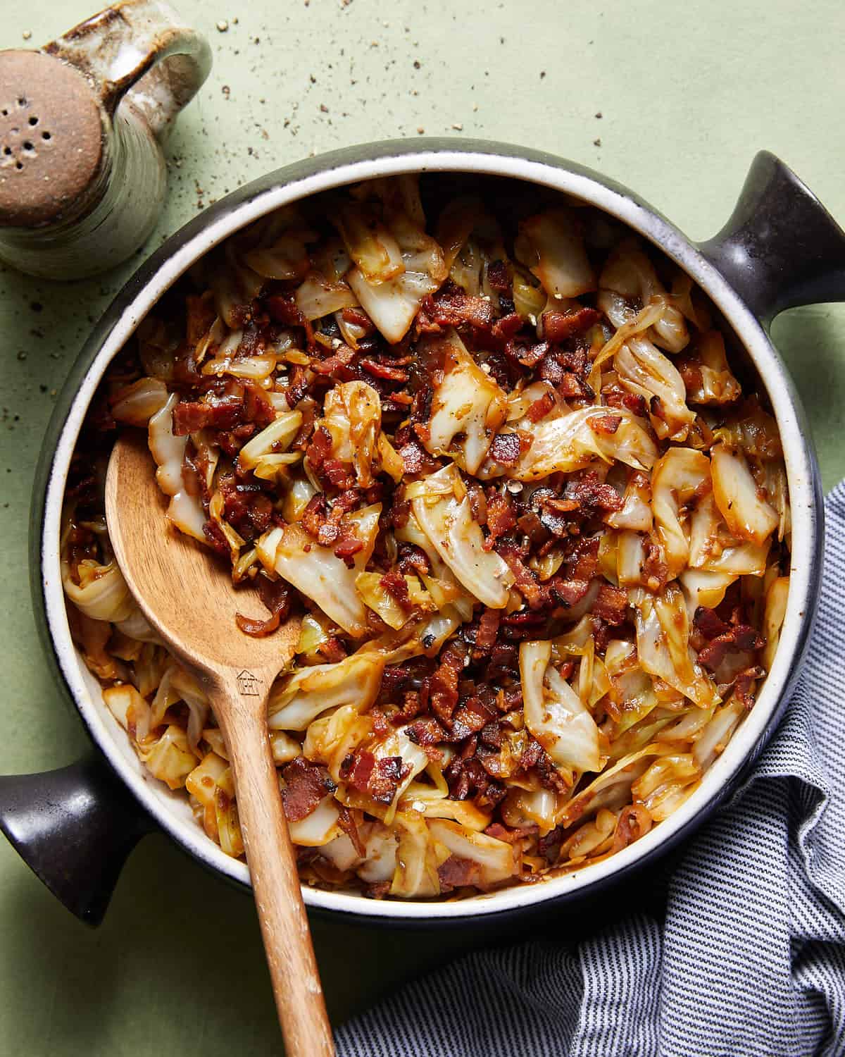 Overhead image of fried cabbage with bacon & onions in black pot. 