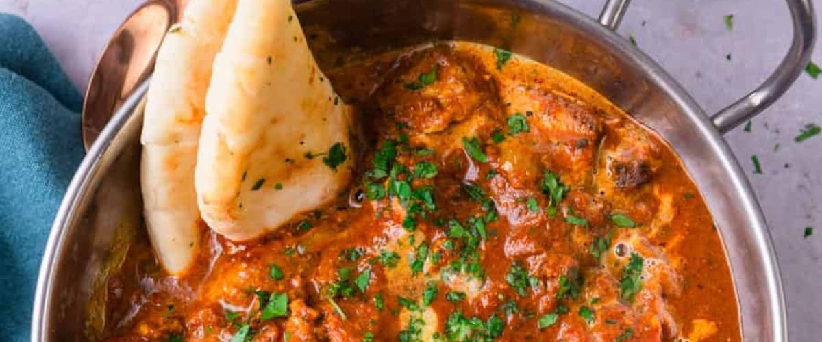 Chicken tikka masala with garnish and naan.