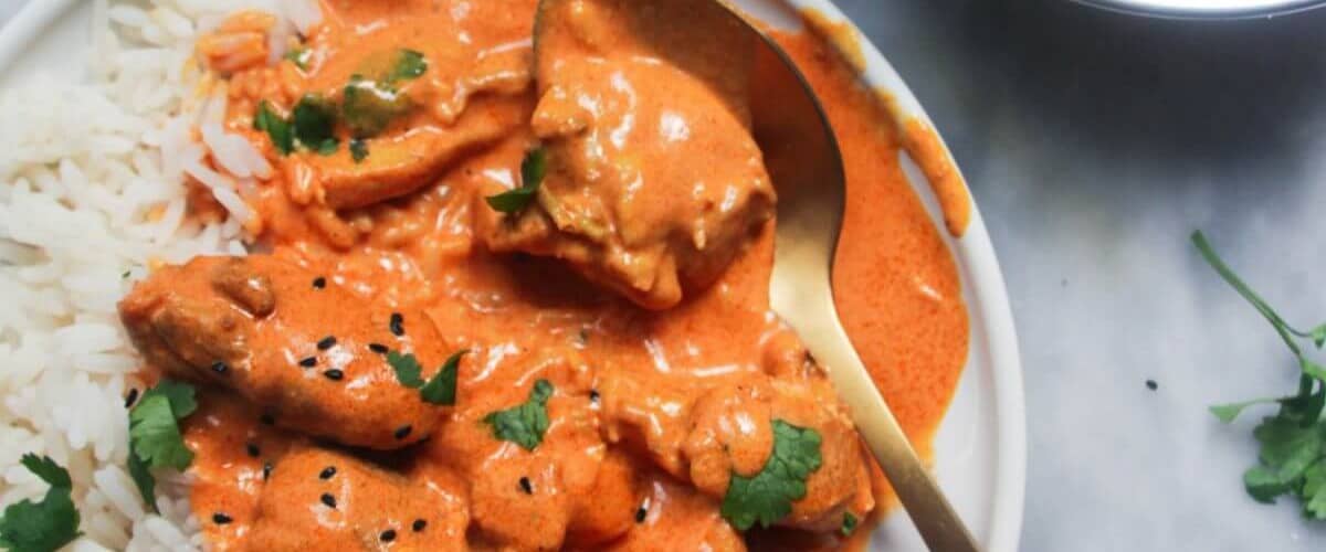 New Zealand style butter chicken in white dish with garnish.