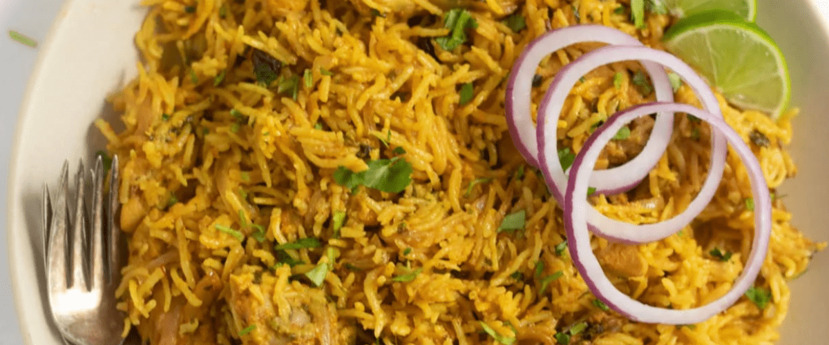 Instant pot chicken biryani with garnish in white bowl.