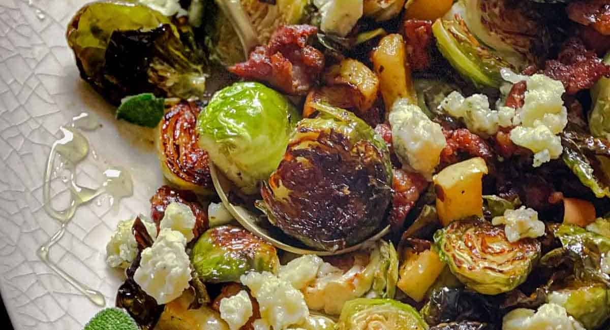 A photo of brussels sprouts with sausage and honey.