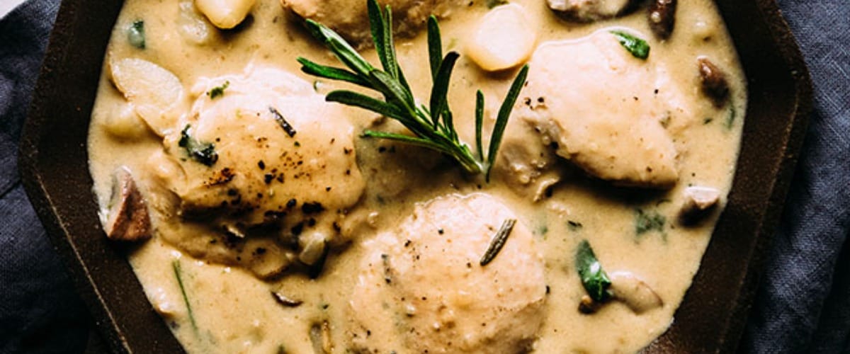 Creamy one pan chicken and potatoes in black dish with garnish.