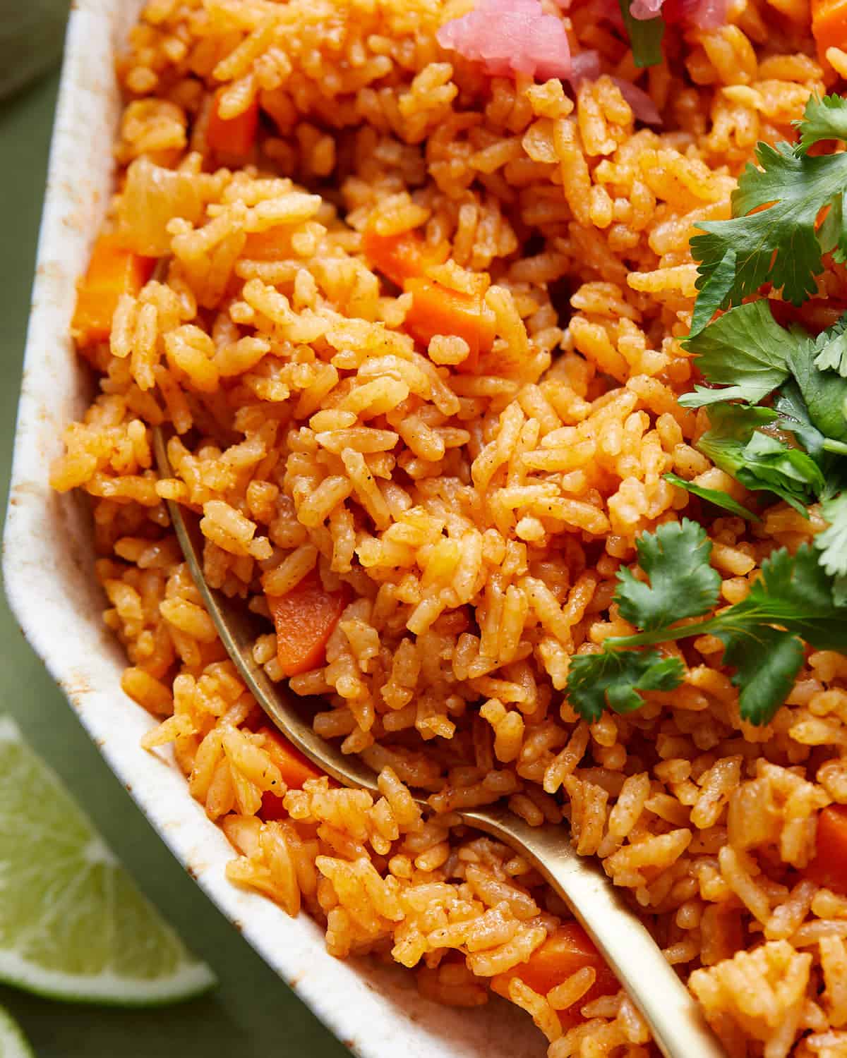 Up close image of Mexican red rice in white dish with spoon.