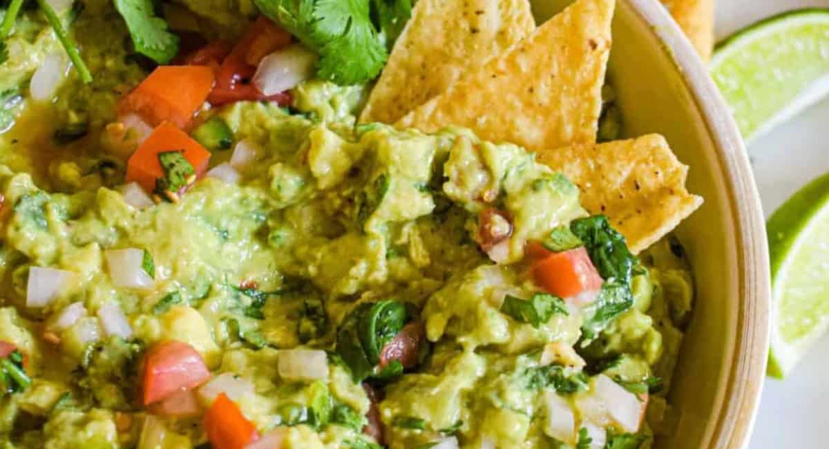 Overhead image of guacamole with chips and garnish.