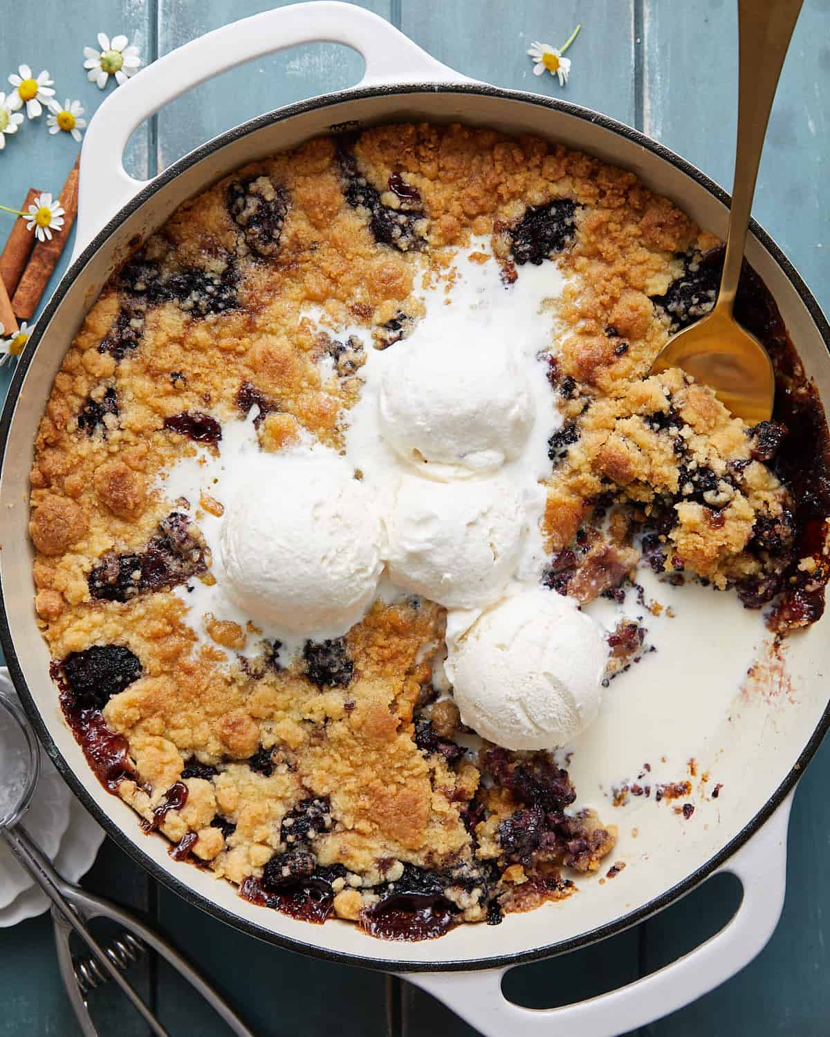 Overhead image of dutch oven blackberry cobbler with vanilla ice cream.