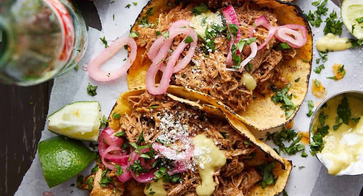 Overhead image of traditional carnitas tacos with garnish.