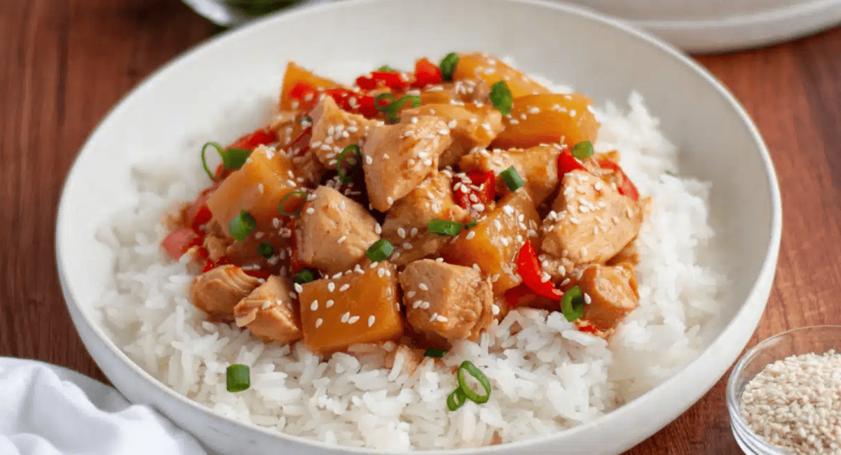 Overhead image of crockpot Hawaiian chicken on bed of rice in white dish.