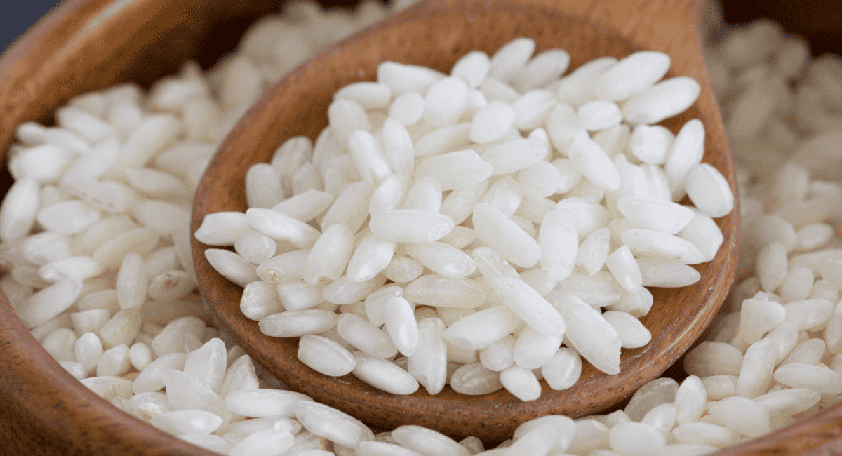 Image of arborio rice on wooden spoon.