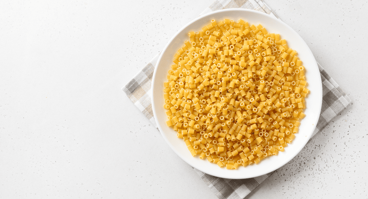 Overhead image of ditalini pasta in white bowl.