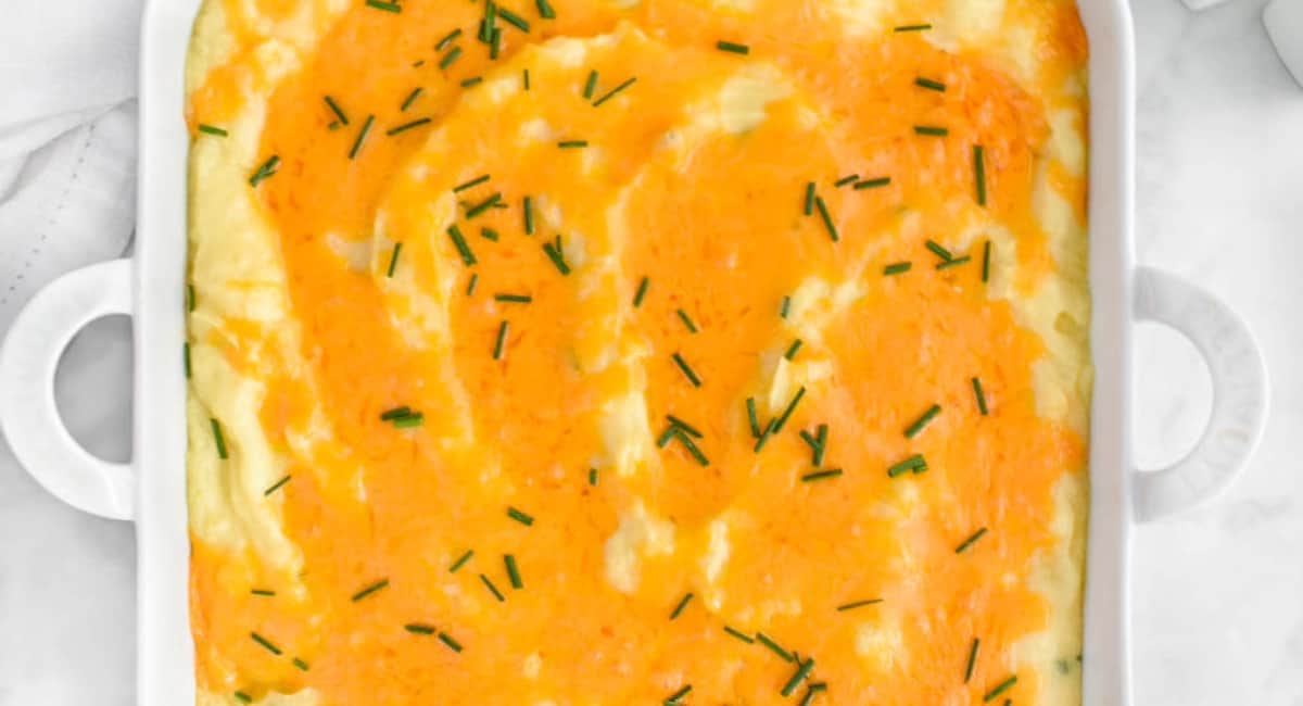 Overhead image of cheesy baked mashed potatoes with garnish. 