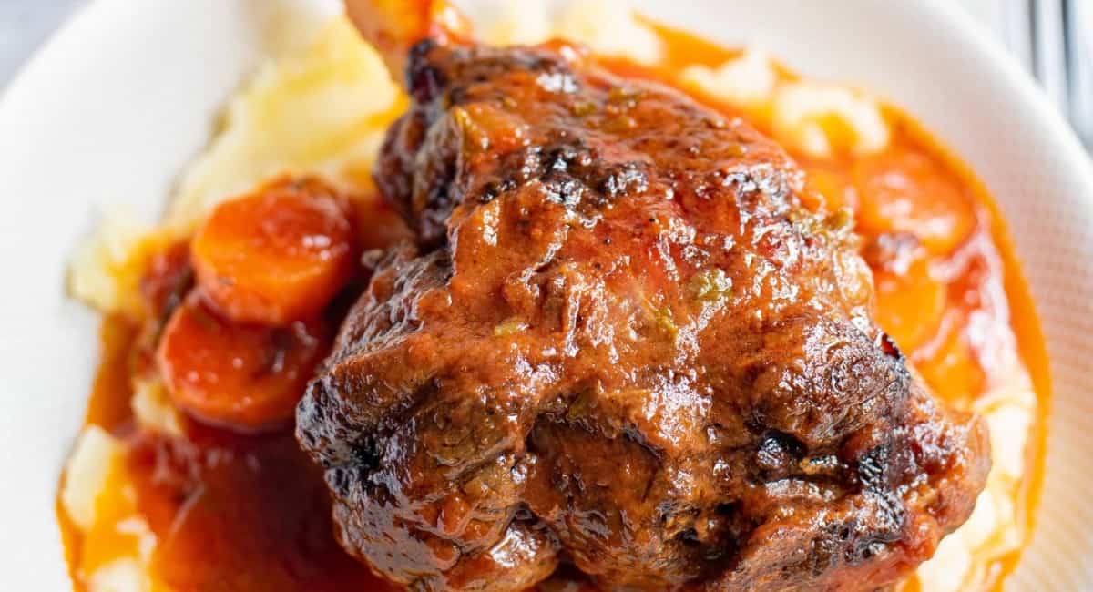 Overhead image of braised lamb shanks with mashed potatoes and carrots.