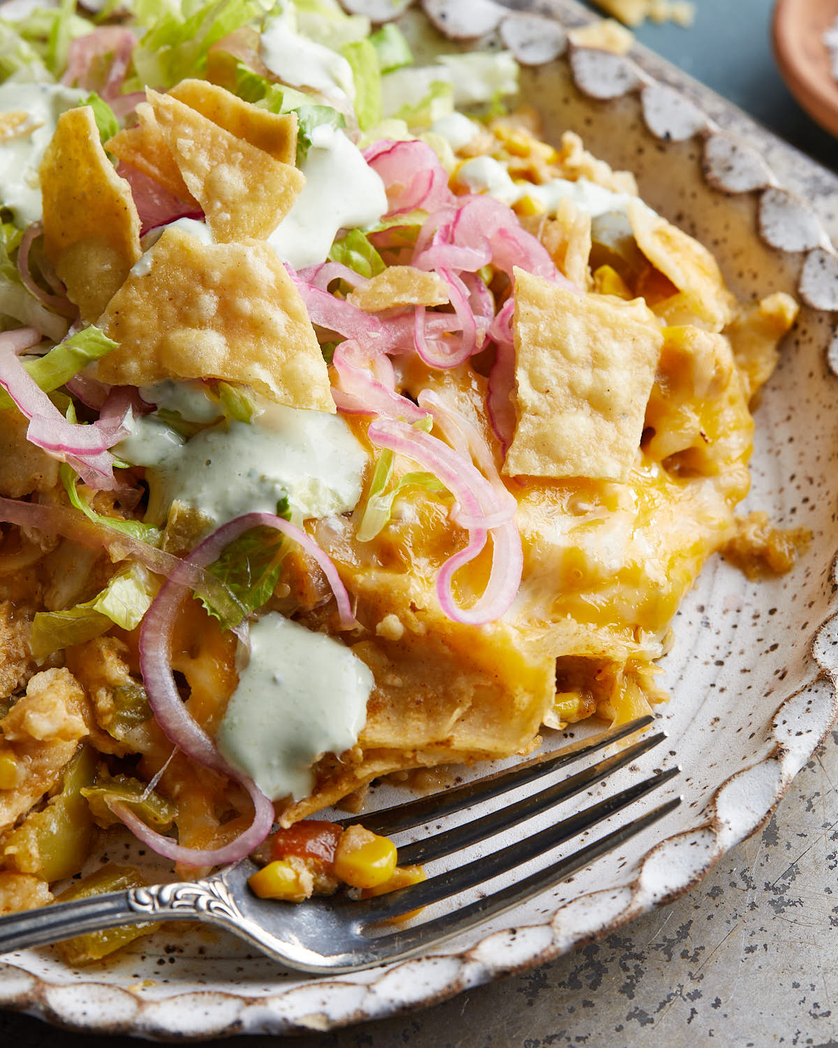 Up close image of slow cooker chicken enchilada casserole on speckled dish.