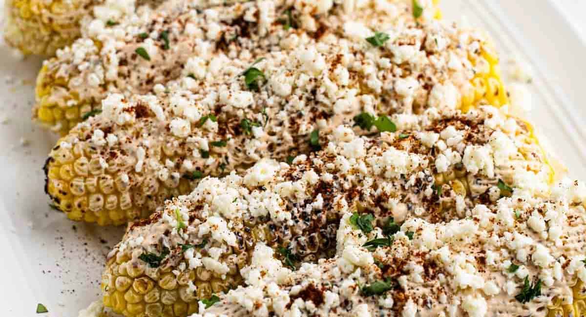 Overhead image of Mexican corn on the cob with garnish. 