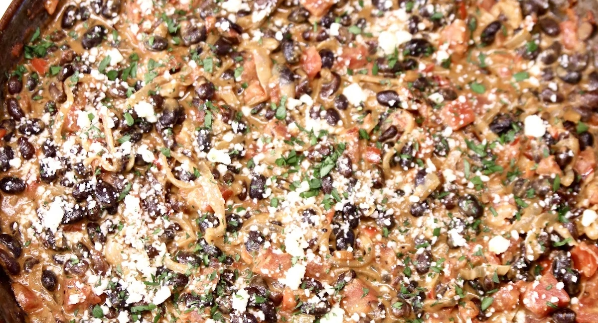 Overhead image of black bean skillet with garnish. 