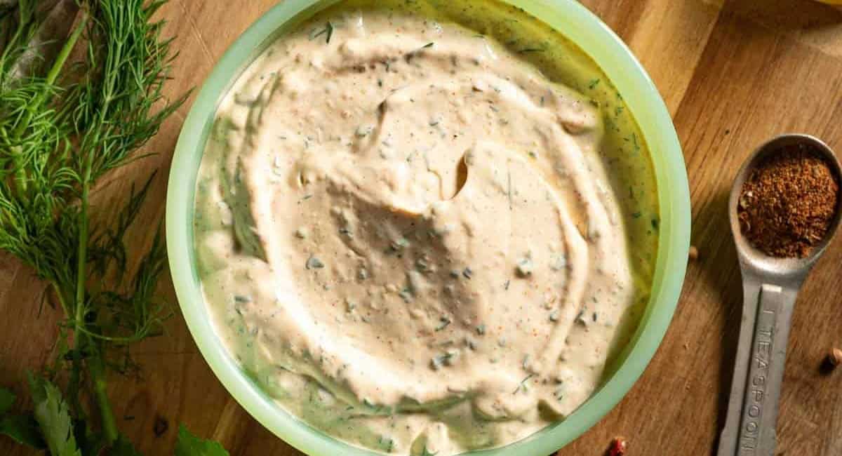 Overhead image of homemade cajun ranch sauce in green dish. 