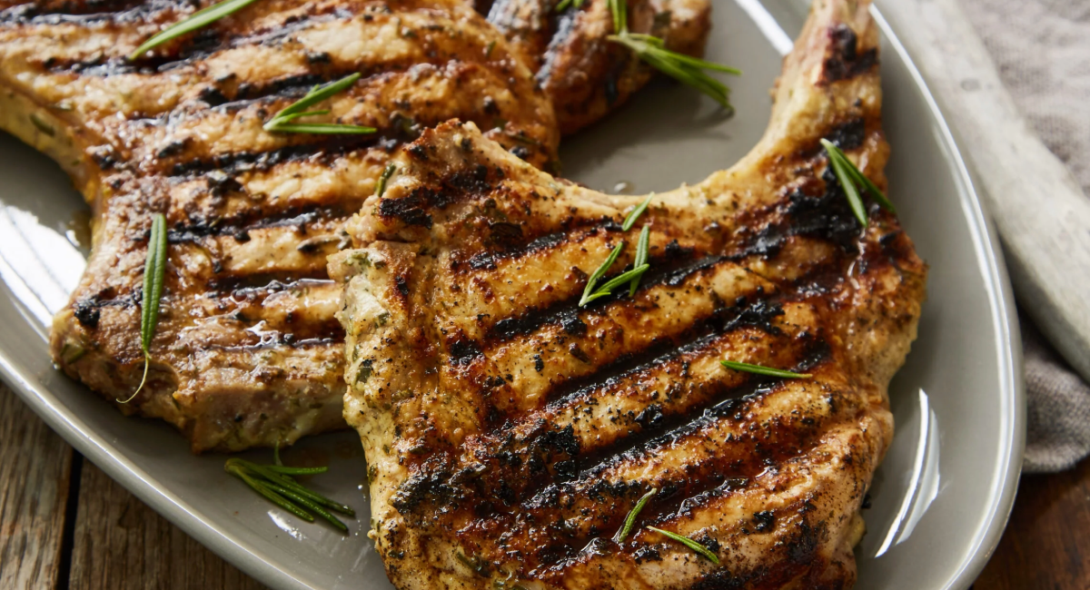 Overhead image of grilled pork chops with rosemary dijon marinade on white dish. 