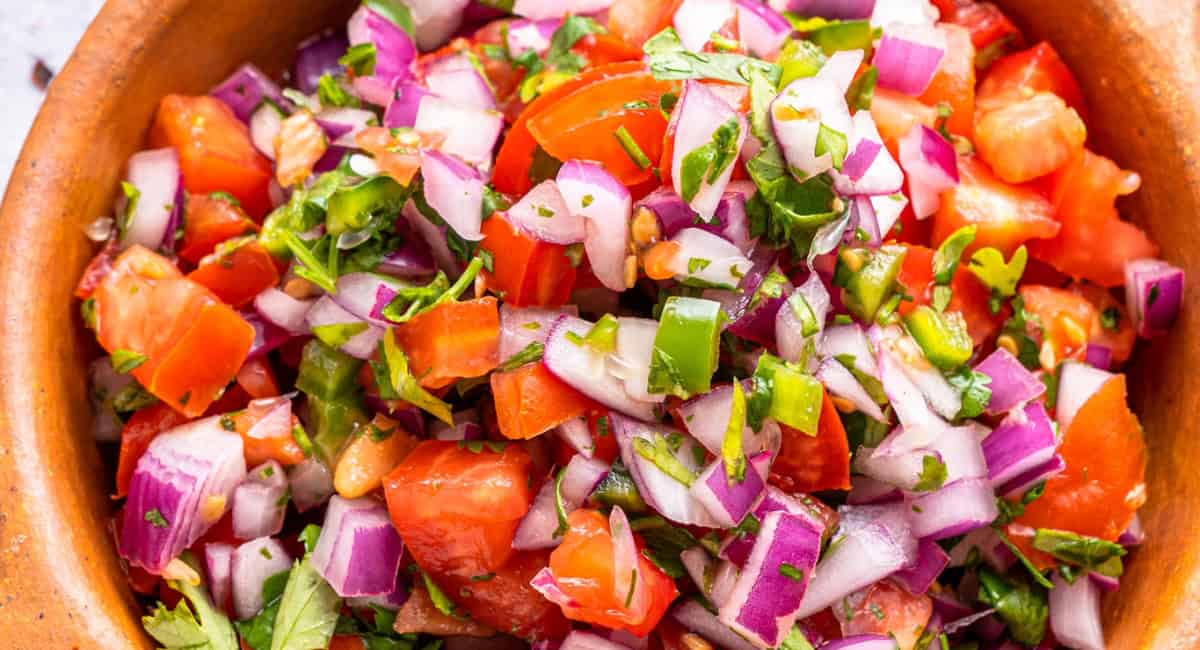Overhead image of homemade pico de gallo in brown dish. 