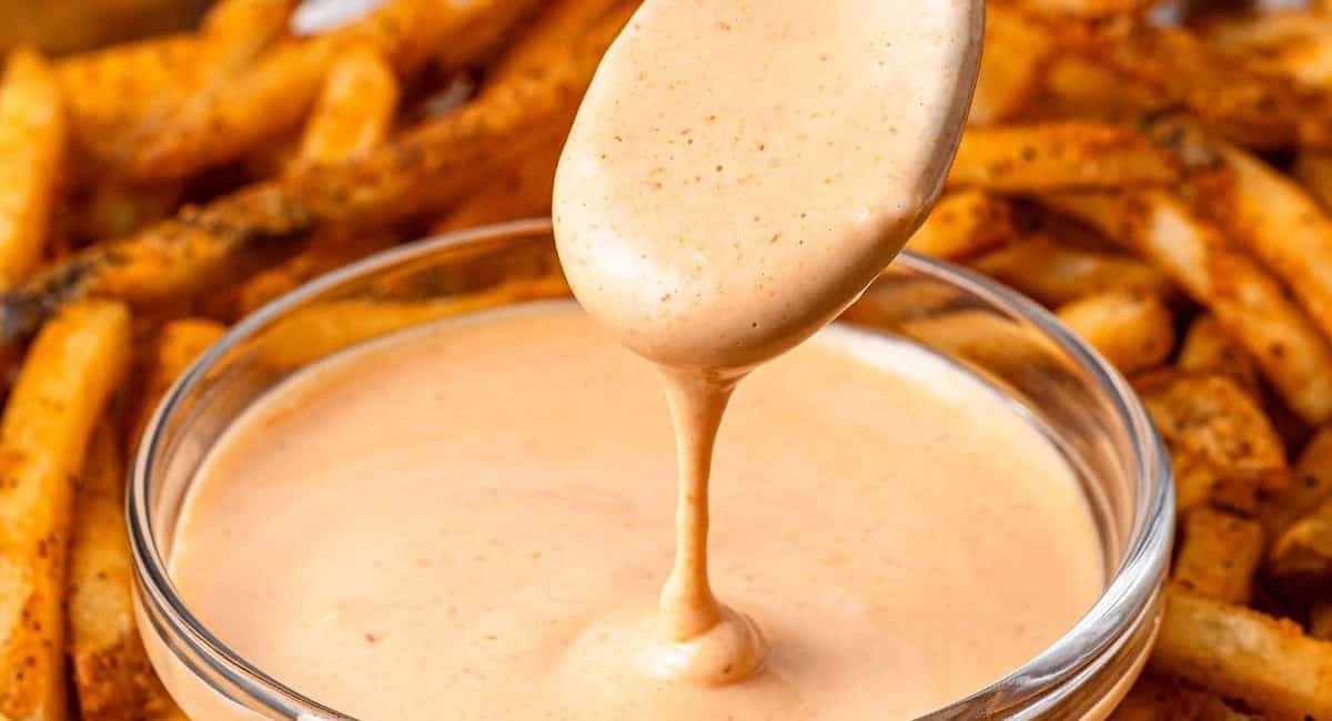 Up close image of sriracha aioli with fries in the background. 