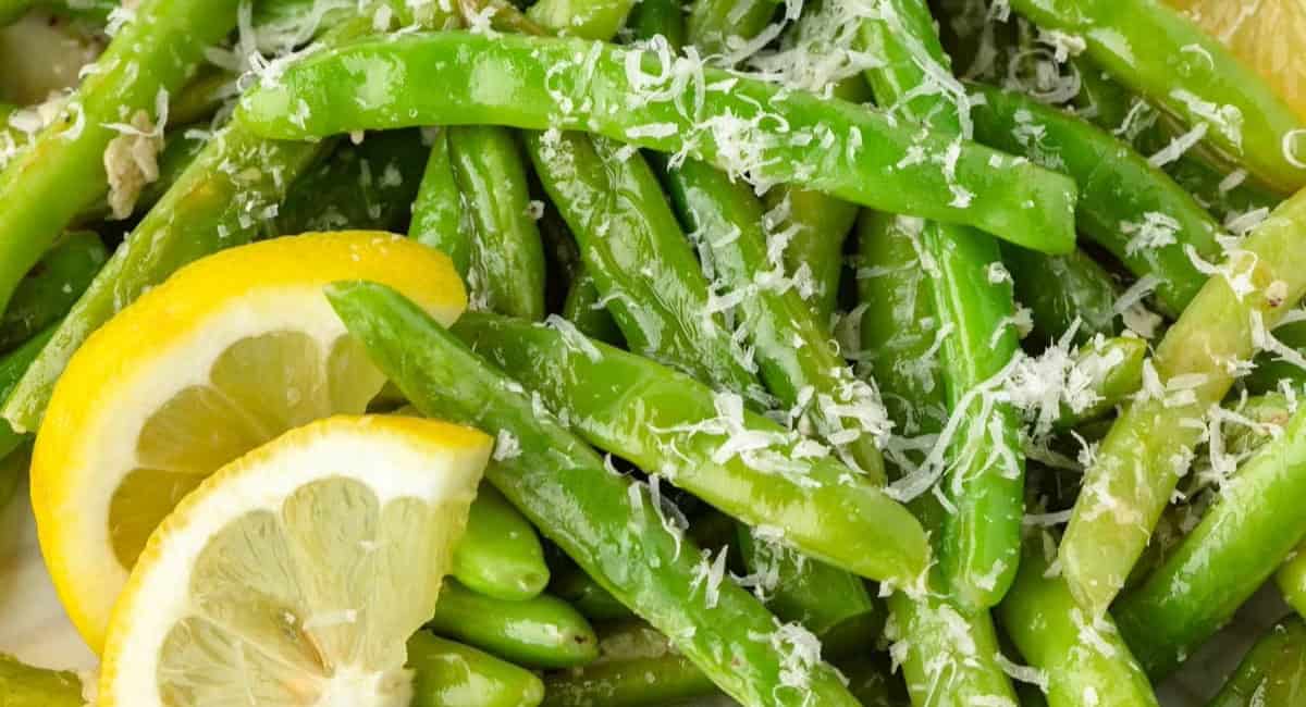 Overhead image of garlic parmesan green beans with lemon garnish. 