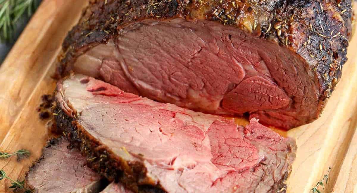 Overhead image of prime rib recipe on wooden cutting board. 