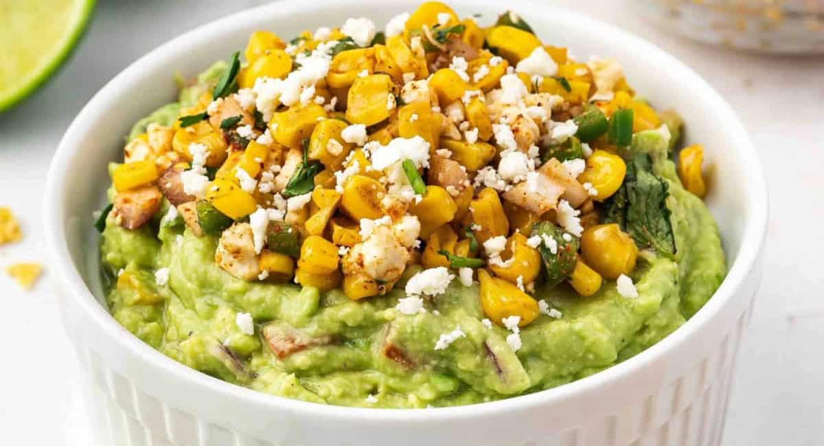 Overhead image of authentic Mexican street corn guacamole with garnish in white bowl. 