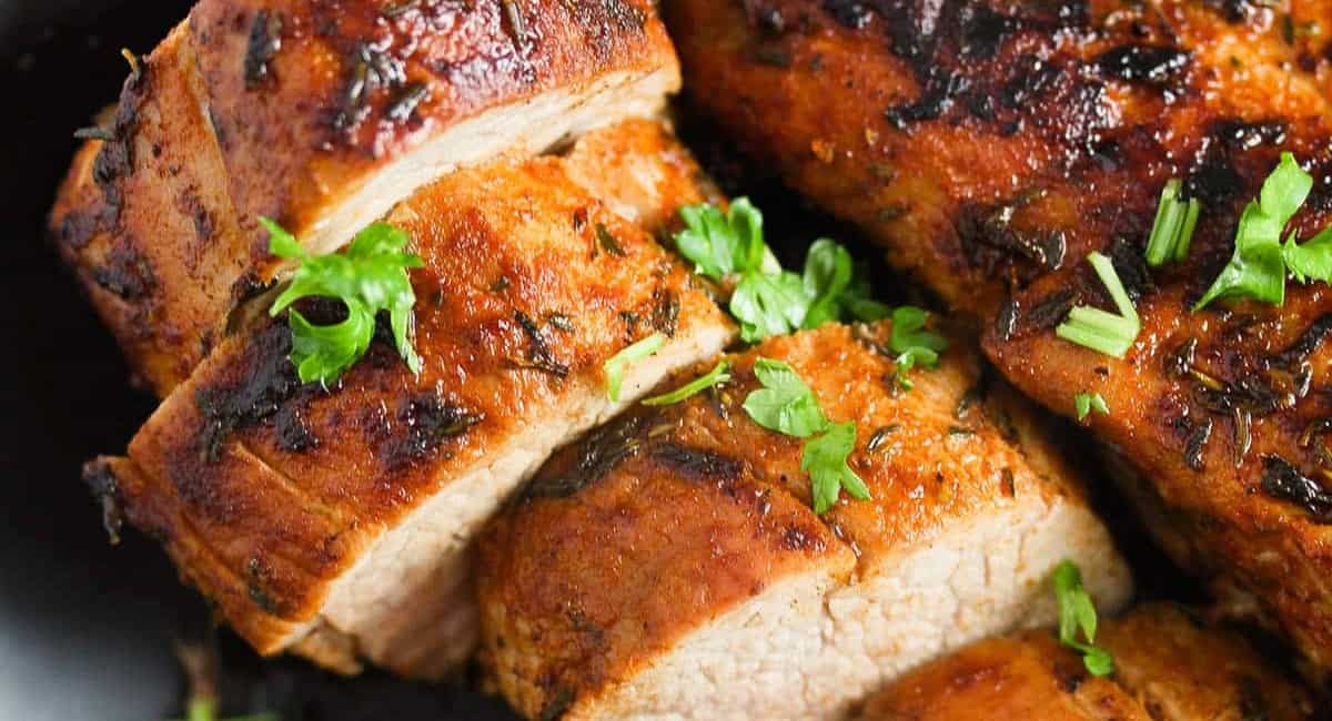 Up close image of cast iron pork tenderloin with garnish. 