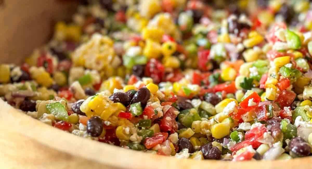 Up close image of black bean & corn dip with feta recipe in brown bowl. 