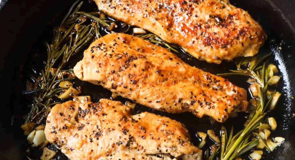 Overhead image of cast iron skillet chicken breast with garnish. 