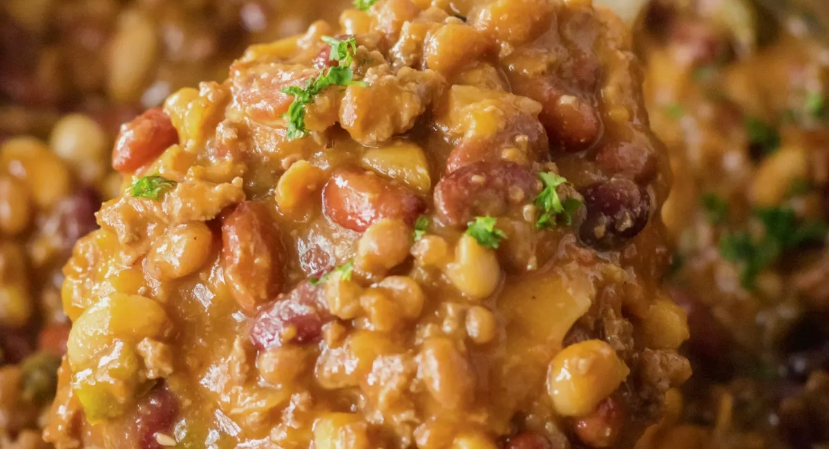 Overhead image of slow cooker cowboy beans with garnish. 