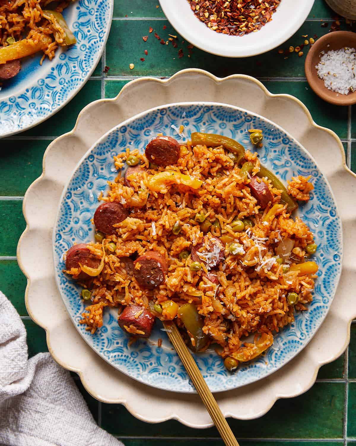 Overhead image of chicken sausage and rice with parmesan topping on white plate with gold fork.